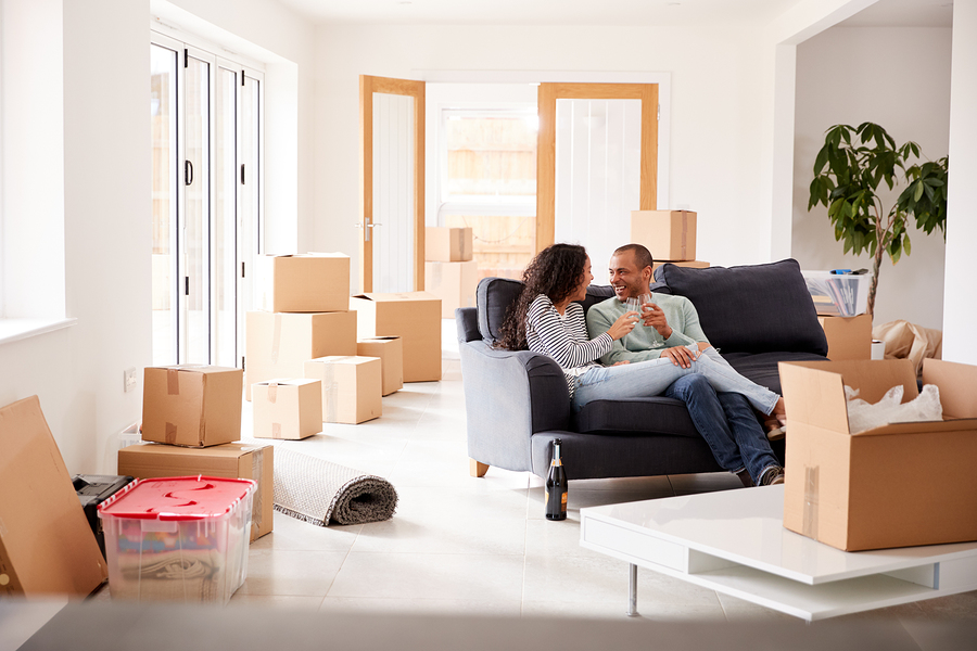 Couple in their bright new living room surrounded by boxes celebrating purchase of home for sale by owner