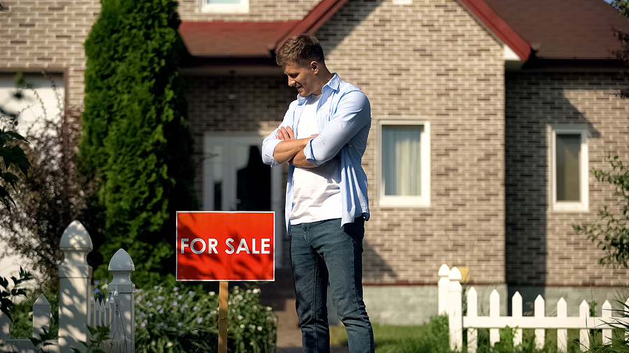 Homeowner admiring his home's for sale sign in front of his house that he's selling for sale by owner